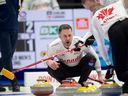 Le capitaine canadien Brad Gushue crie au deuxième E.J. Harnden, à droite, et au premier Geoff Walker alors qu'ils brossent une pierre du troisième Mark Nichols dans la maison lors de la quatrième manche du match de vendredi soir contre la Suède.