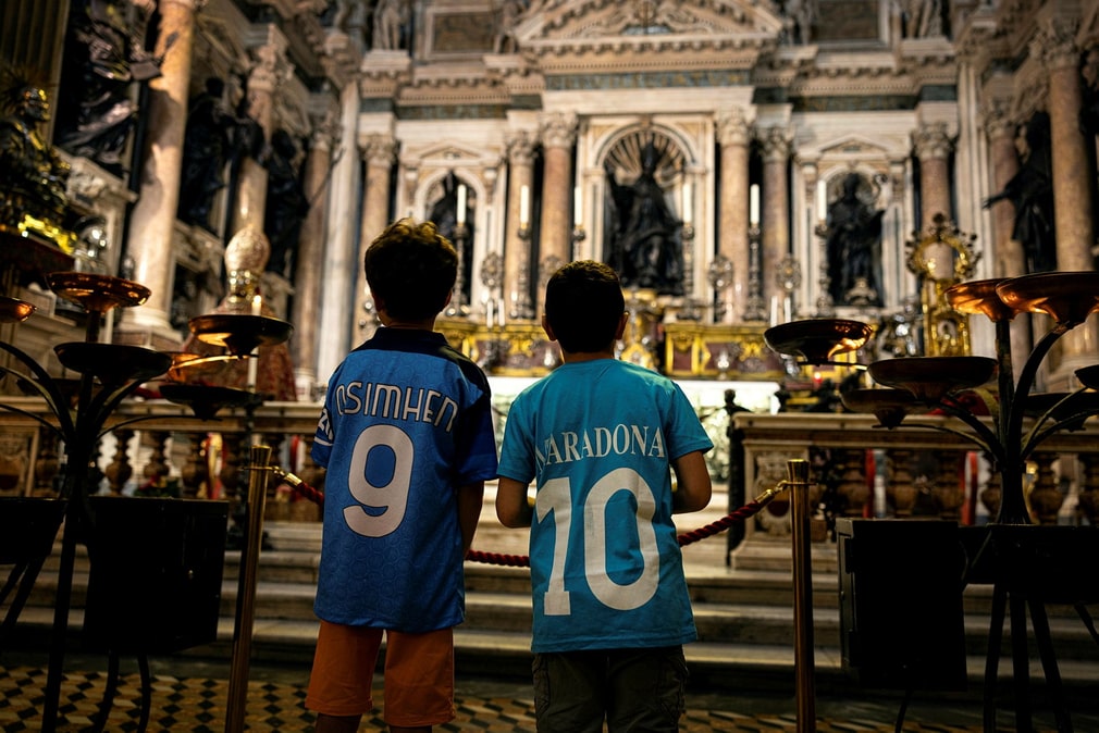 Emanuele et Lorenzo attendent le miracle de janvier dans la cathédrale de Naples. Comme tant d'autres, les garçons portent des maillots napolitains, l'un au nom de la nouvelle star Victor Osimhen, l'autre à celui de l'éternelle idole Diego Maradona.