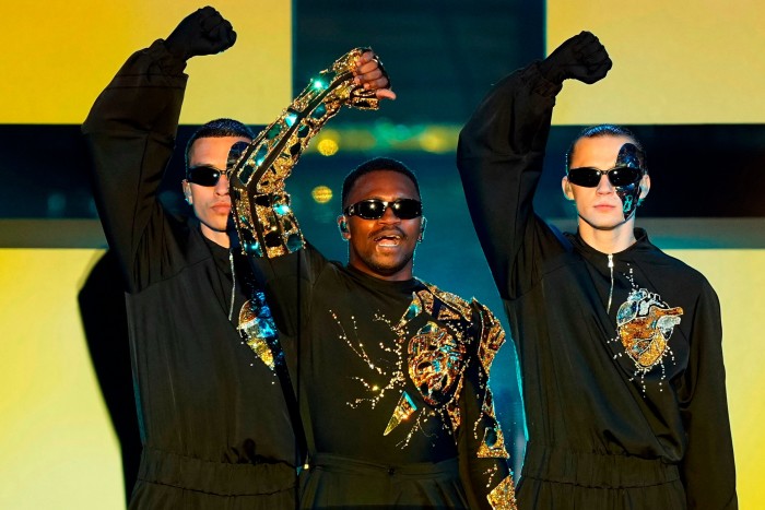 Des hommes portant des lunettes de soleil lèvent le poing devant un fond jaune et bleu.