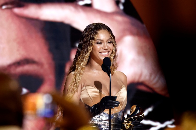 Beyonce sourit alors qu'elle reçoit le Grammy de l'album de musique électronique et de danse pour Renaissance. Elle porte une robe de soirée en soie beige et ses cheveux sont lâchés.