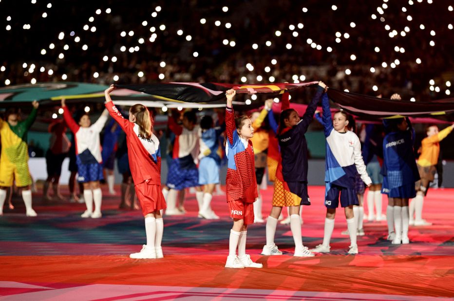 Des enfants tiennent des drapeaux pendant la cérémonie d'ouverture.