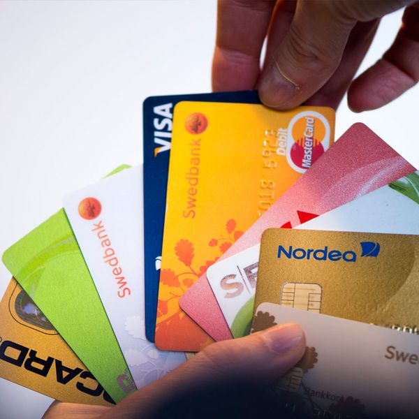 Photo : SVT. TT. Femme à gauche, main avec plusieurs cartes bancaires à droite.